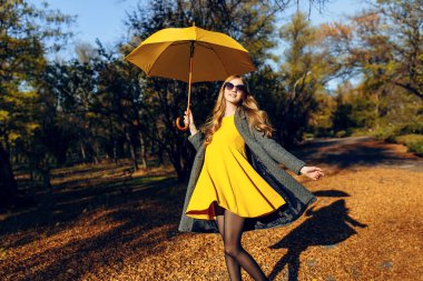 Mutlu kız turuncu yapraklı ağaçların arasında parkta yürüyor ve eğleniyor..