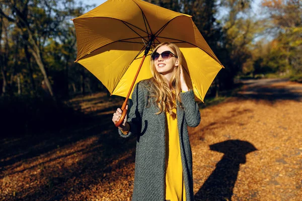 Mädchen mit gelbem Regenschirm, im Park mit gelben Blättern, Herbstzeit — Stockfoto