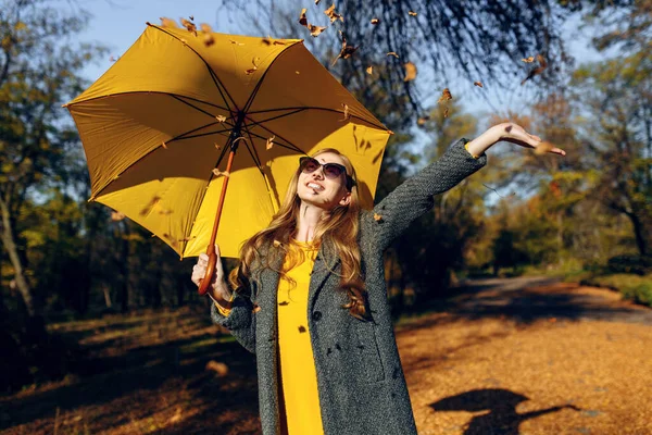 노란 우산을 두른 행복 한 소녀, 공원의 가을 온기를 즐기는 모습 — 스톡 사진