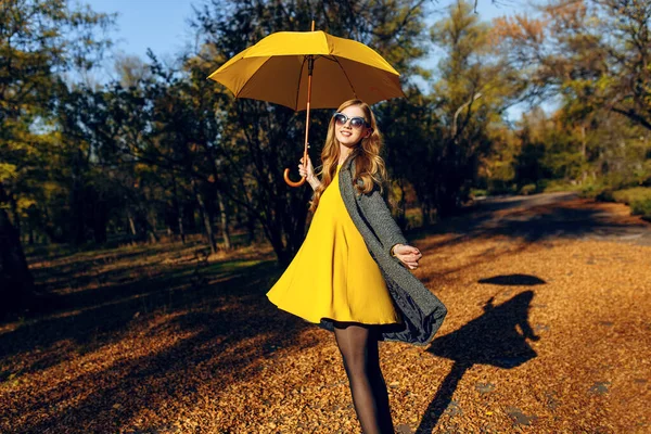 Gelukkig meisje spinnen en genieten van een wandeling in het park tussen de bomen met oranje bladeren. — Stockfoto