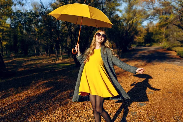 Glückliches Mädchen, das sich dreht und einen Spaziergang im Park zwischen Bäumen mit orangefarbenen Blättern genießt. — Stockfoto