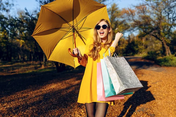 Стильная девушка после успешного шопинга в парке с сумками — стоковое фото