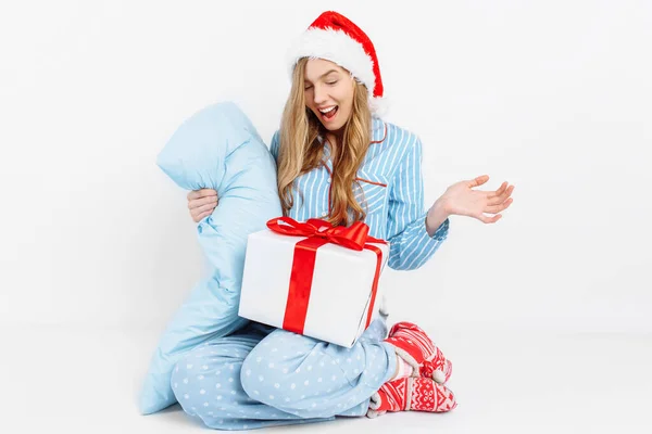 Manhã de Natal. Menina bonita feliz, em pijama de Natal e chapéu de Papai Noel, recebeu um presente no dia de Natal — Fotografia de Stock