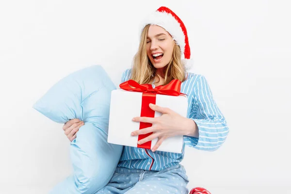Manhã de Natal. Menina bonita feliz, em pijama de Natal e chapéu de Papai Noel, recebeu um presente no dia de Natal — Fotografia de Stock
