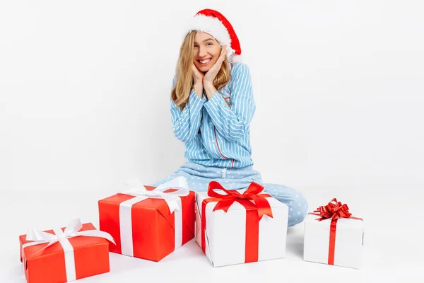 Manhã de Natal. Menina bonita feliz, em pijama de Natal e chapéu de Papai Noel, recebeu muitos presentes de Natal — Fotografia de Stock