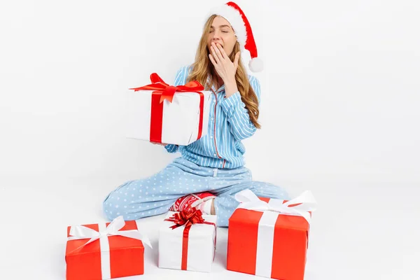 Vánoční ráno. Šťastná krásná mladá dívka, v vánoční pyžamo a Santa klobouk, obdržel mnoho vánočních dárků — Stock fotografie