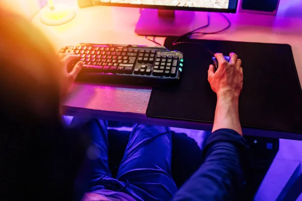 professional gamer playing computer games online with headphones, in a room with neon light.