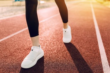 Stadyumun etrafında koşan spor ayakkabılı kadın ayaklarının yakın çekimi. Sabah koşusu.