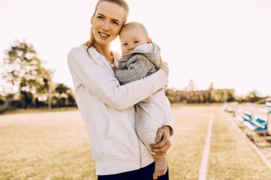 Temiz havada mutlu bir aile. Anne açık havada küçük çocuğuyla gülüp oynuyor.