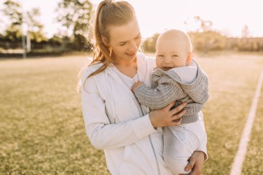 Temiz havada mutlu bir aile. Anne açık havada küçük çocuğuyla gülüp oynuyor.