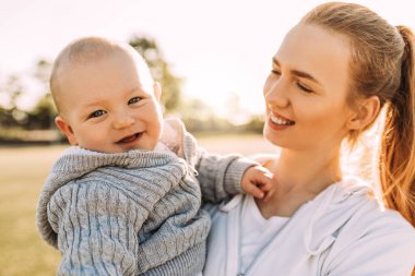 Temiz havada mutlu bir aile. Anne yazın dışarıda çocuğuyla gülüp oynuyor.