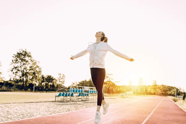 Fitness woman doing cardio interval training outdoors. A girl in sports clothes trains jumps against the background of the dawn