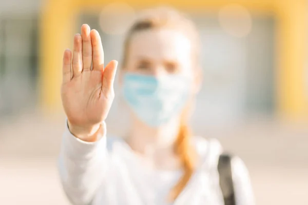 医療用保護マスクの若い女性が建物の裏に立っていて 屋外に停止標識を示しています 隔離コロナウイルス — ストック写真
