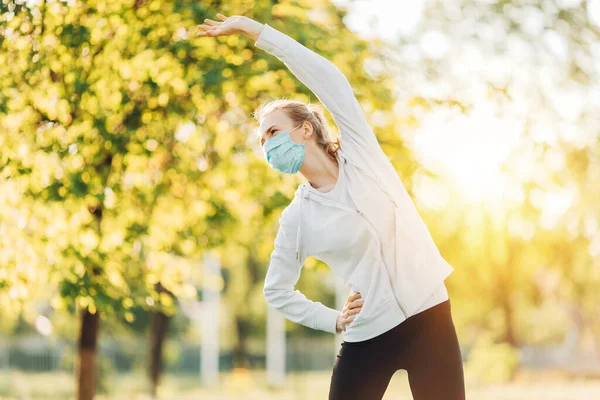 朝公園でスポーツをする医療用保護マスクの若い女性 — ストック写真