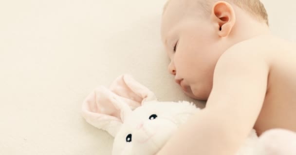 Small child in a diaper, sleeping sweetly in his crib with a plush toy — Stock Video