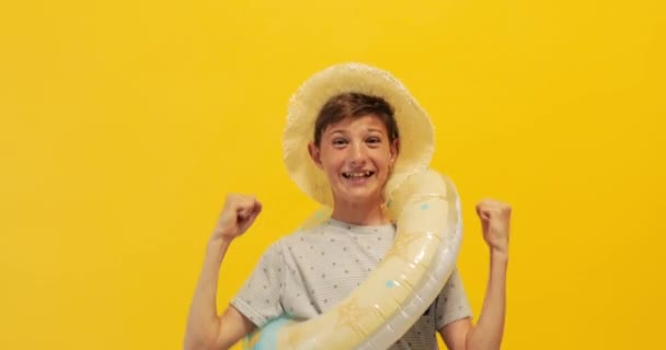 Glücklicher Teenager, der mit einem aufblasbaren Seekreis steht und den Sieg feiert, isoliert auf gelbem Hintergrund — Stockvideo