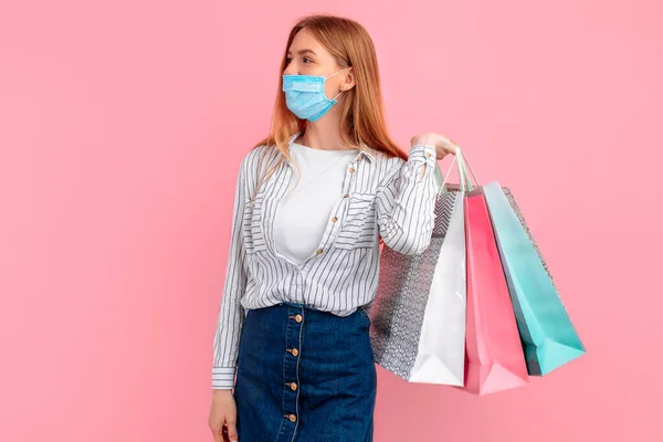 Boldog Lány Orvosi Maszkban Arcán Bevásárlószatyrokkal Pózol Rózsaszín Háttérrel Vásárlás — Stock Fotó