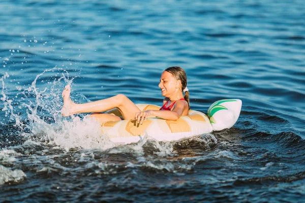 快乐的孩子在一个充气的圆环上漂浮在海面上 暑假和孩子们在一起 儿童游泳用具和服装 — 图库照片