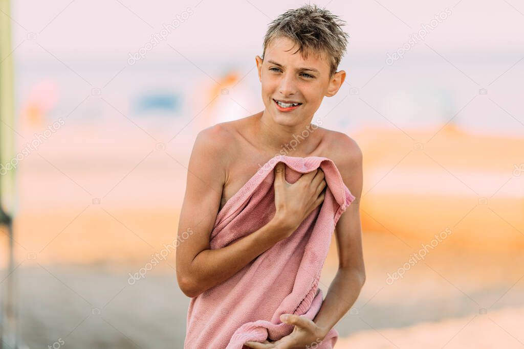 happy teenager wipes himself with a towel after swimming in the sea. Summer holidays, vacations