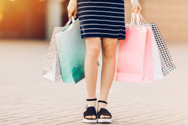 Alışverişe gidelim. Kadının elinde alışveriş merkezinin arka planında renkli alışveriş torbaları var. Moda.