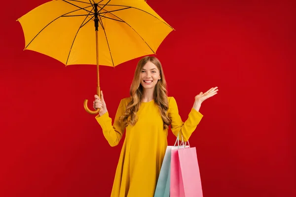 Excited Shaken Young Woman Yellow Umbrella Shopping Bags Red Background — Stock Photo, Image