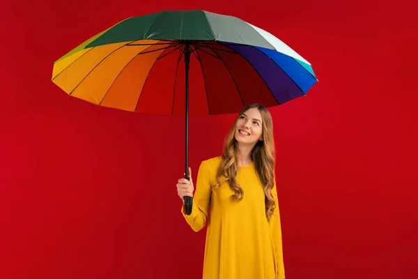 虹色の傘を持つ幸せな若い女性は 赤い背景に 秋のコンセプト — ストック写真