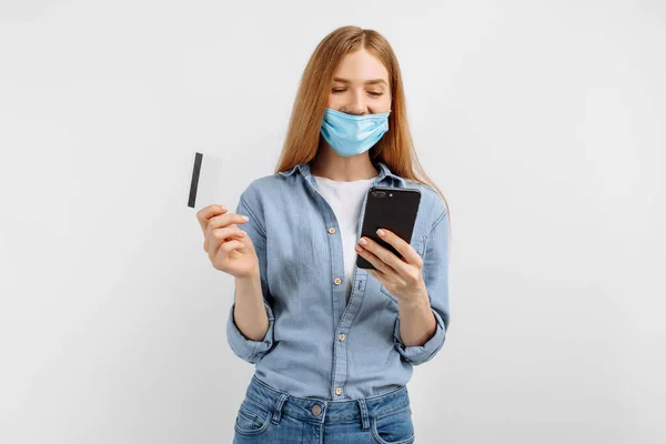 Fiatal Orvosi Maszkban Arcán Műanyag Hitelkártyával Mobiltelefonnal Fehér Alapon — Stock Fotó