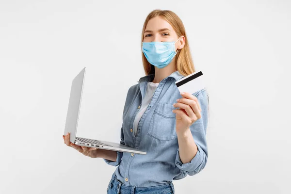 Fiatal Orvosi Maszkban Arcán Laptoppal Műanyag Hitelkártyával Kezében Fehér Alapon — Stock Fotó