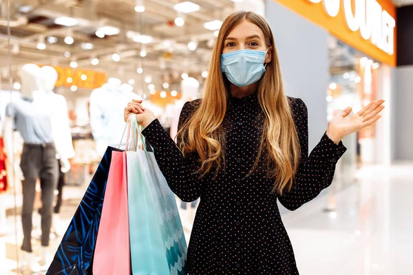 Boldog Fiatal Orvosi Védőmaszkban Arcán Bevásárlószatyrokkal Sétál Bevásárlóközponton — Stock Fotó