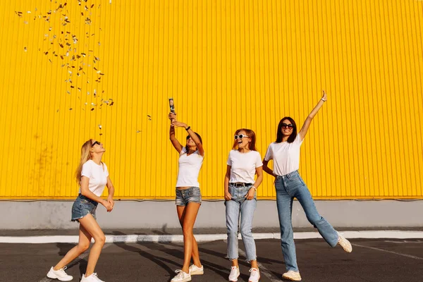 Jovens Amigas Felizes Divertindo Com Confete Fundo Parede Amarela Shopping — Fotografia de Stock