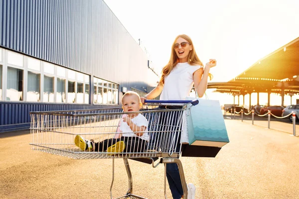 Mama Małym Dzieckiem Wózku Sklepowym Spacerując Ulicą Pobliżu Centrum Handlowego — Zdjęcie stockowe