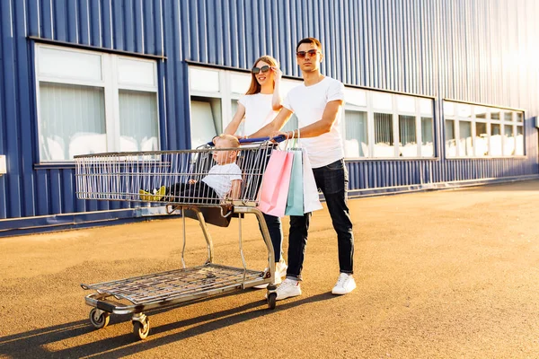 Szczęśliwa Rodzina Dzieckiem Torbami Zakupy Wózkiem Tle Centrum Handlowego Zakupy — Zdjęcie stockowe