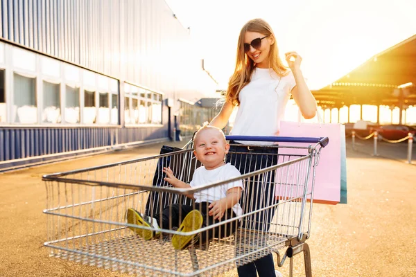 Podekscytowany Młoda Matka Dzieckiem Torby Zakupy Wózek Sklepowy Pobliżu Centrum — Zdjęcie stockowe