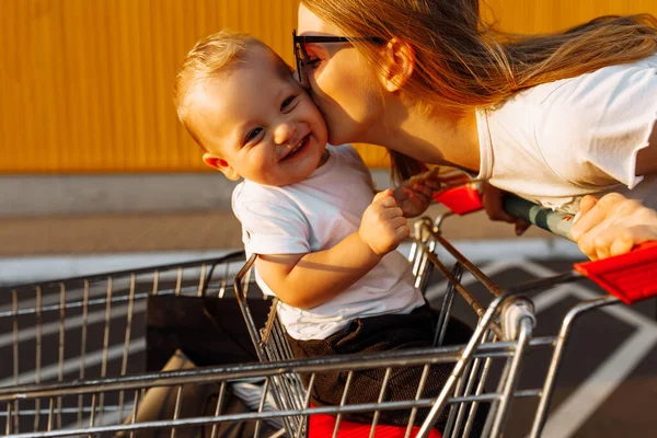 Mama Robi Zakupy Małym Dzieckiem Siedzącym Wózku Ulicy Tle Żółtej — Zdjęcie stockowe