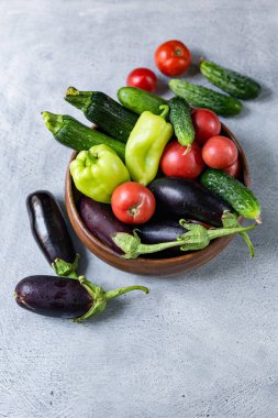 ahşap bir kase içinde sebze karışımı; domates, patlıcan, salatalık, biber