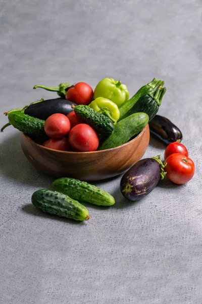 ahşap bir kase içinde sebze karışımı; domates, patlıcan, salatalık, biber