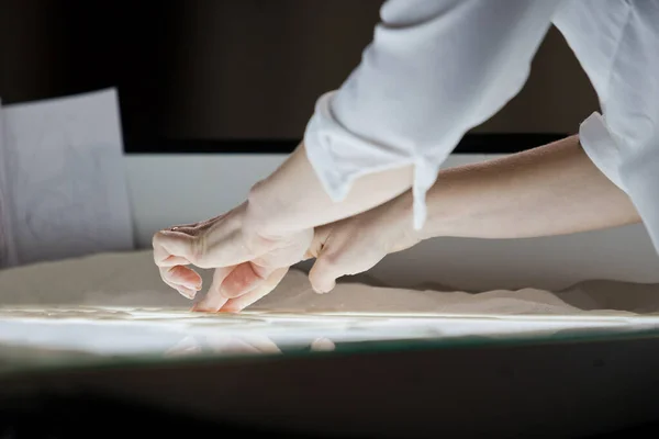 Sand animation.The girl's arms, drawing sand