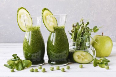 İki bardak bir close-up salatalık, elma ve Beyaz ahşap zemin üzerine nane taze ev yapımı meyve suyu ile. Alan, seçici odak sığ derinliği