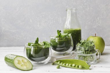 İki bardak bir close-up salatalık, elma ve Beyaz ahşap zemin üzerine nane taze sıkılmış meyve suyu ile. Alan, seçici odak sığ derinliği