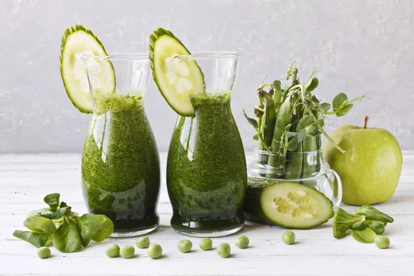Ev yapımı yeşil smoothie Close-up taze ıspanak, bezelye, salatalık ve elma Beyaz ahşap zemin üzerinde yapılan