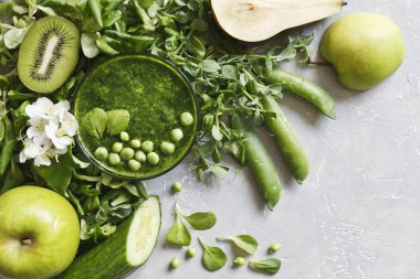 Taze ıspanak, bezelye, salatalık, armut ve elma gri arka plan üzerine ev yapımı yeşil smoothie Close-up. Üstten görünüm.