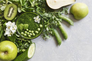 Taze ıspanak, bezelye, salatalık, armut ve elma gri arka plan üzerine ev yapımı yeşil smoothie Close-up. Üstten görünüm.