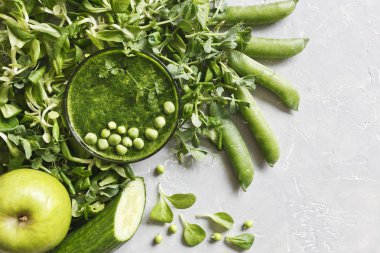 Gri arka plan üzerinde taze ıspanak, bezelye, salatalık ve elma ile ev yapımı Yeşil yüzlü üstten görünüm. 