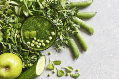 Gri arka plan üzerinde taze ıspanak, bezelye, salatalık ve elma ile ev yapımı Yeşil yüzlü üstten görünüm. 