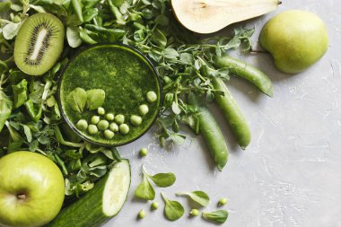 Gri arka plan üzerinde taze armut, bezelye, salatalık, kivi ve elma ile ev yapımı Yeşil yüzlü üstten görünüm. 