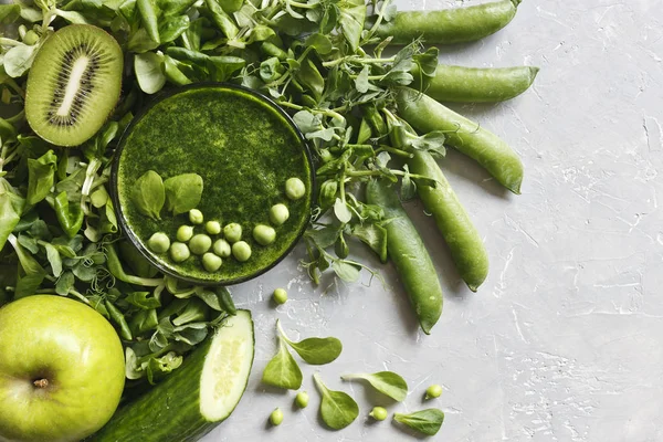 Gri arka plan üzerinde taze ıspanak, bezelye, salatalık, kivi ve elma ile ev yapımı Yeşil yüzlü üstten görünüm. 