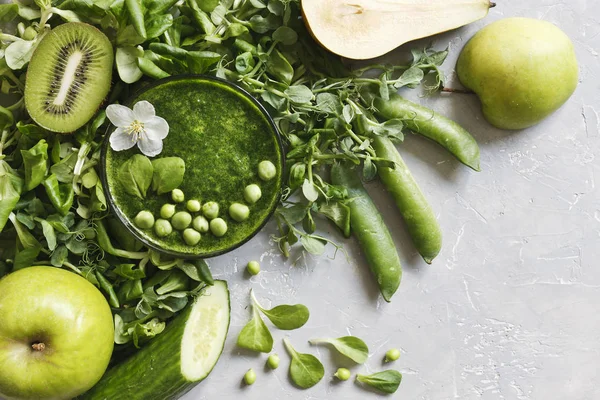 Gri arka plan üzerinde taze armut, bezelye, salatalık, kivi ve elma ile ev yapımı Yeşil yüzlü üstten görünüm. 