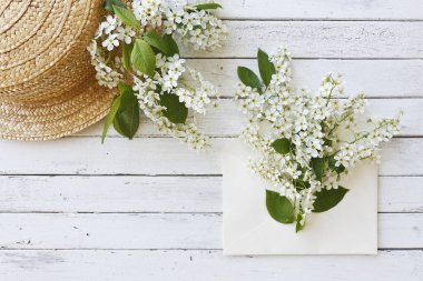 Şapka yakınındaki güzel çiçekli ağaç dalları Beyaz ahşap zemin üzerinde zarf yakın çekim fotoğraf. Üstten görünüm, seçici odak, sığ derinlik-in tarla