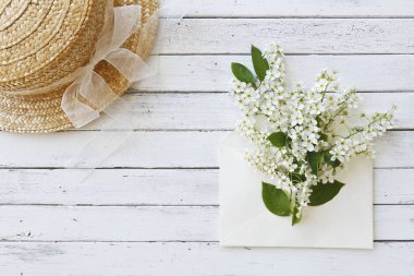 Şapka yakınındaki güzel çiçekli ağaç dalları Beyaz ahşap zemin üzerinde zarf yakın çekim fotoğraf. Üstten görünüm, seçici odak, sığ derinlik-in tarla