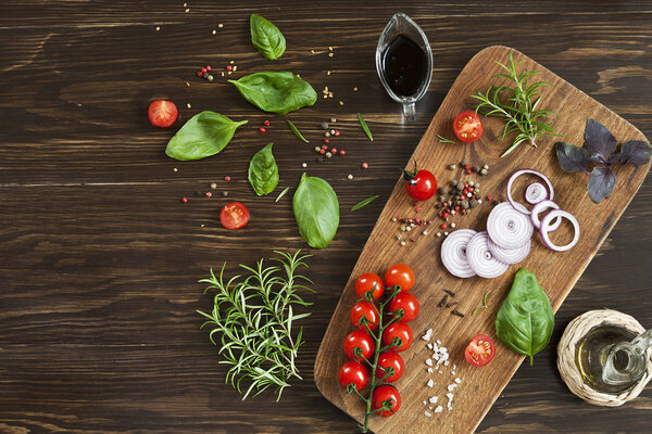 close-up photo of fresh tomatoes, onions, rosemary with green basil leaves and oil on wooden board